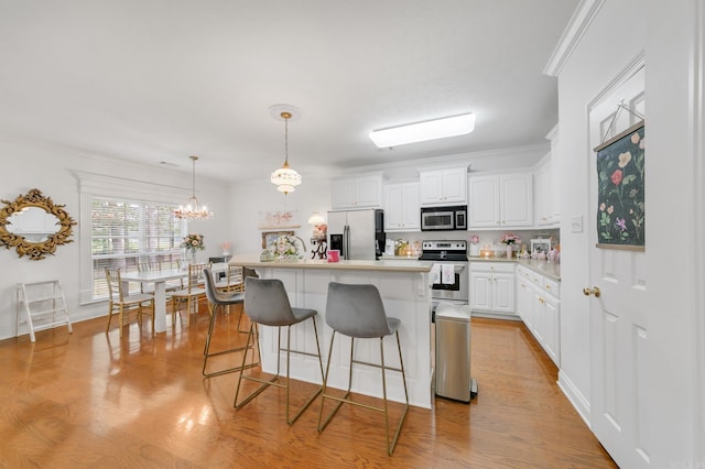 43 Earnhardt Cir, Cabot, AR 72023 - kitchen featuring appliances with stainless steel finishes, a kitchen breakfast bar, white cabinets, light countertops, and crown molding