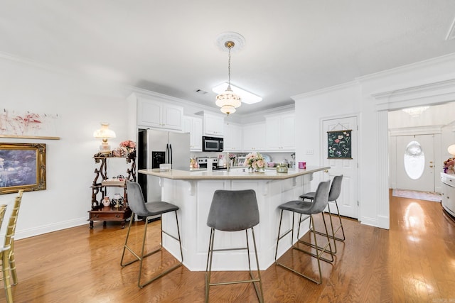 43 Earnhardt Cir, Cabot, AR 72023 - kitchen with appliances with stainless steel finishes, light countertops, wood finished floors, a breakfast bar area, and ornamental molding