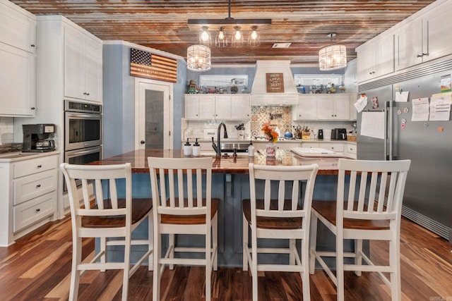 10820 W Sardis Rd, Bauxite, AR 72011 - kitchen with appliances with stainless steel finishes, premium range hood, a sink, backsplash, and white cabinets