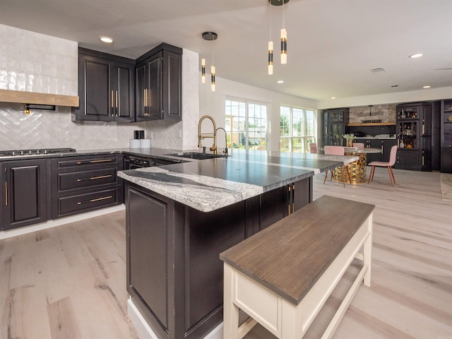 15 Brandywine Ln, Little Rock, AR 72227 - kitchen with a sink, stainless steel gas stovetop, light stone counters, tasteful backsplash, and light wood-style floors