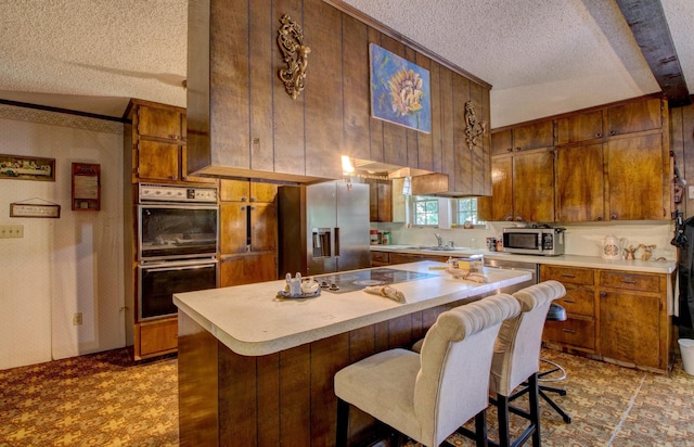 826 Carson Bridge Rd, Lonoke, AR 72086 - kitchen with a textured ceiling, stainless steel appliances, light countertops, brown cabinets, and a sink