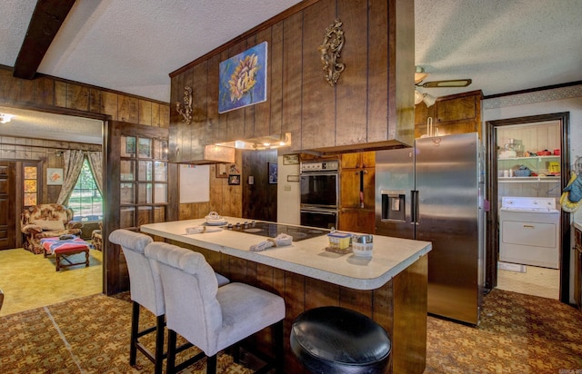 826 Carson Bridge Rd, Lonoke, AR 72086 - kitchen featuring washer / dryer, a textured ceiling, stainless steel fridge with ice dispenser, double wall oven, and wood walls