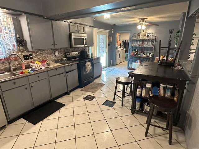 6625 Chateau Dr, Little Rock, AR 72209 - kitchen featuring black electric range oven, separate washer and dryer, stainless steel microwave, gray cabinets, and dark countertops
