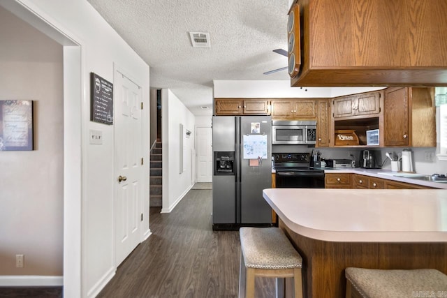 6221 Bray Dr, Benton, AR 72019 - kitchen with appliances with stainless steel finishes, light countertops, dark wood-style floors, brown cabinets, and a peninsula