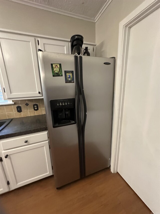 213 S Adcock, Dumas, AR 71639 - kitchen with stainless steel refrigerator with ice dispenser, white cabinets, dark countertops, wood finished floors, and ornamental molding