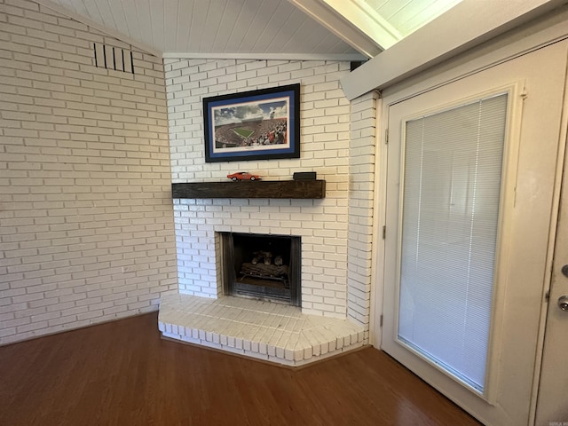 213 S Adcock, Dumas, AR 71639 - unfurnished living room featuring wood finished floors, brick wall, a brick fireplace, and lofted ceiling