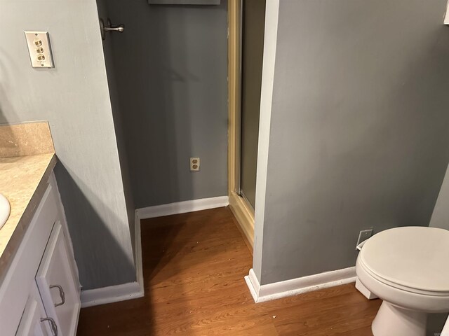 213 S Adcock, Dumas, AR 71639 - bathroom with vanity, wood finished floors, toilet, baseboards, and an enclosed shower