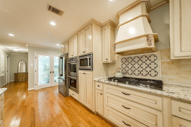 21221 Unicorn Ln, Roland, AR 72135 - kitchen featuring ornamental molding, stainless steel appliances, cream cabinetry, light wood-style flooring, and tasteful backsplash