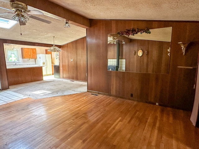 33 W Lakeshore Dr, Cherokee Village, AR 72529 - unfurnished living room featuring wood walls, a ceiling fan, a textured ceiling, light wood-style floors, and beam ceiling