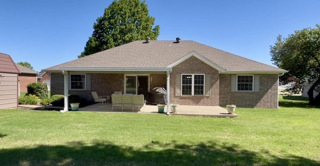 back of property with a patio, a yard, brick siding, and an outdoor living space