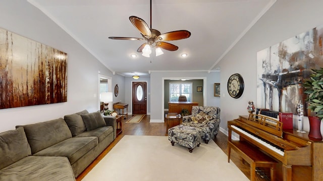 living room with lofted ceiling, wood finished floors, a ceiling fan, ornamental molding, and baseboards