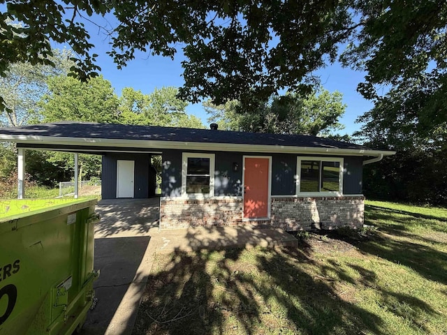 view of front of home featuring driveway, a carport, brick siding, and a front lawn