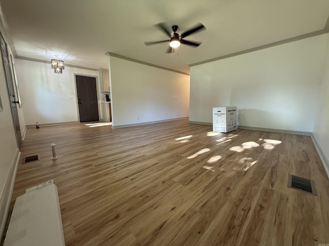 unfurnished living room featuring ornamental molding, ceiling fan, wood finished floors, baseboards, and a chandelier