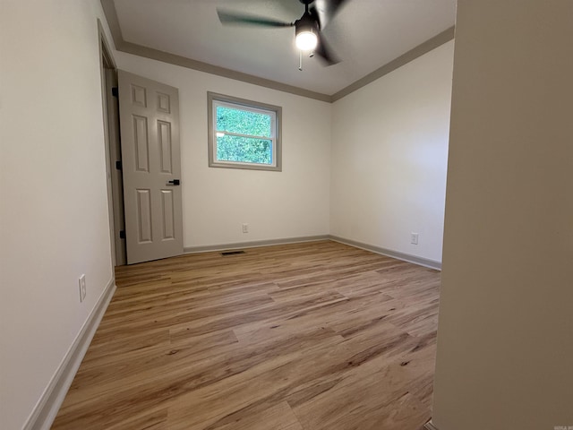empty room featuring light wood-type flooring, baseboards, ceiling fan, and ornamental molding