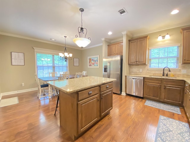 3008 Lilly Ln, Benton, AR 72019 - kitchen featuring appliances with stainless steel finishes, a sink, a breakfast bar, wood finished floors, and ornamental molding