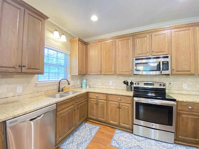 3008 Lilly Ln, Benton, AR 72019 - kitchen featuring appliances with stainless steel finishes, a sink, crown molding, light wood-style flooring, and decorative backsplash