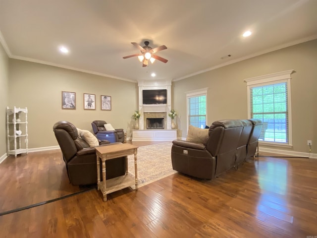 3008 Lilly Ln, Benton, AR 72019 - living area featuring a fireplace with raised hearth, a ceiling fan, dark wood-type flooring, baseboards, and crown molding