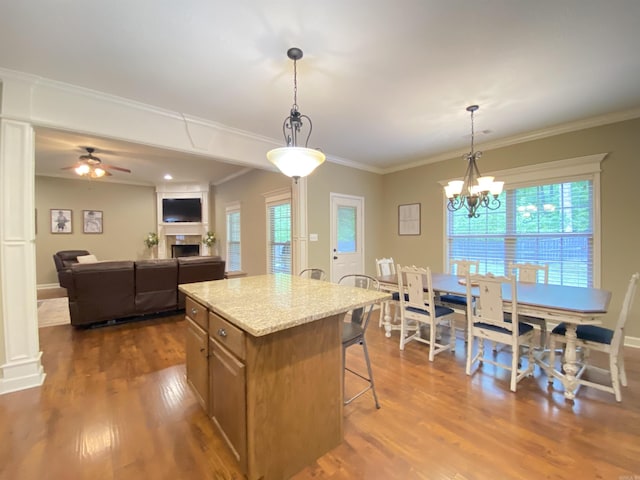 3008 Lilly Ln, Benton, AR 72019 - kitchen with dark wood finished floors, a kitchen bar, a fireplace, pendant lighting, and crown molding