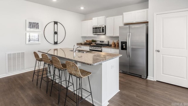 kitchen featuring stainless steel appliances, a sink, white cabinets, a breakfast bar, and recessed lighting