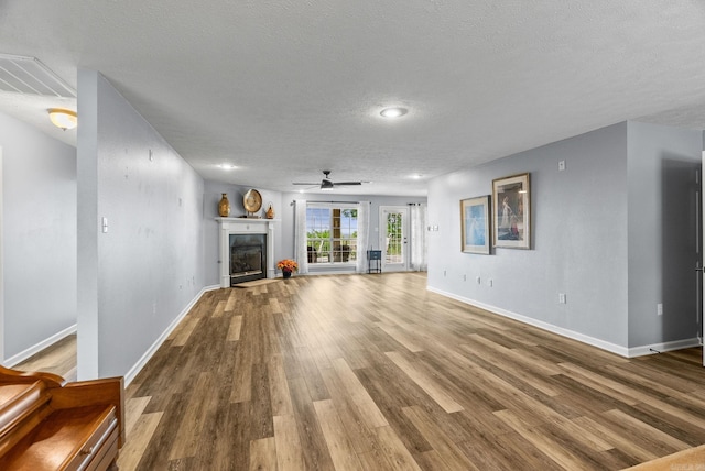 40 Pine Mountain Dr, Conway, AR 72034 - unfurnished living room with ceiling fan, wood finished floors, a textured ceiling, baseboards, and a fireplace