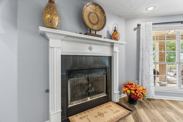 40 Pine Mountain Dr, Conway, AR 72034 - detailed view of wood finished floors, a textured ceiling, a tiled fireplace, and baseboards