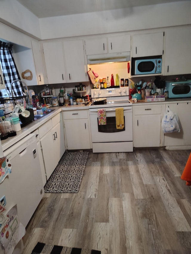 kitchen featuring white appliances, under cabinet range hood, light countertops, and white cabinets