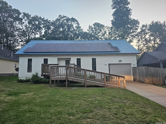 612 Briar St, Sherwood, AR 72120 - rear view of house with roof mounted solar panels, a deck, concrete driveway, and metal roof