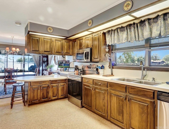 190 Woodlore Pt, Hot Springs, AR 71913 - kitchen featuring appliances with stainless steel finishes, a sink, a peninsula, brown cabinets, and light countertops
