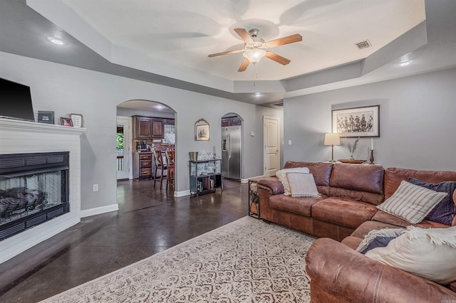 58 Eaglebrook Dr, Conway, AR 72032 - living room with arched walkways, concrete floors, a tray ceiling, ceiling fan, and baseboards