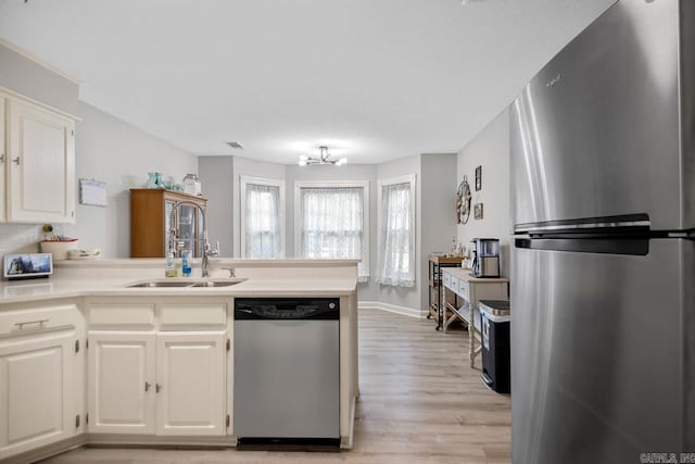 55 Laver Cir, Little Rock, AR 72210 - kitchen with stainless steel appliances, a peninsula, light wood-style floors, light countertops, and white cabinetry