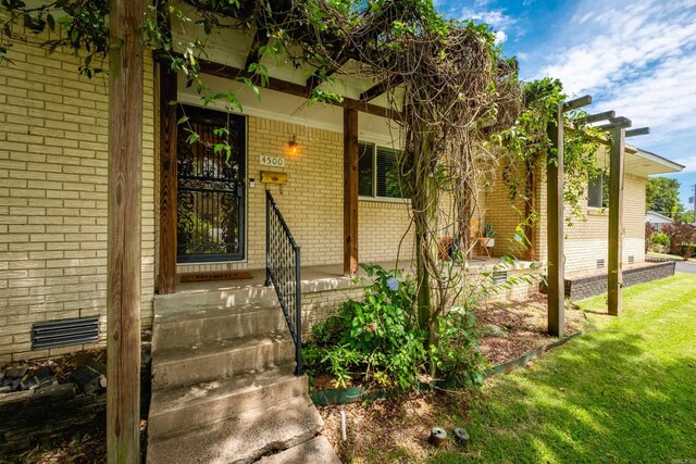 4500 Glenmere Rd, North Little Rock, AR 72116 - doorway to property featuring brick siding, crawl space, a yard, and covered porch