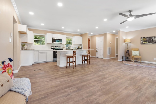 6513 Corsica Dr, North Little Rock, AR 72116 - kitchen featuring appliances with stainless steel finishes, a breakfast bar area, a center island, ornamental molding, and white cabinets