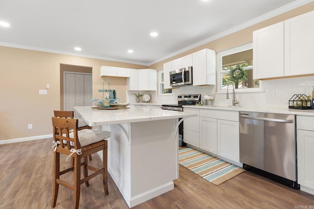 6513 Corsica Dr, North Little Rock, AR 72116 - kitchen with appliances with stainless steel finishes, a sink, a kitchen bar, decorative backsplash, and light wood-type flooring