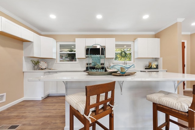 6513 Corsica Dr, North Little Rock, AR 72116 - kitchen featuring stainless steel microwave, white cabinets, backsplash, recessed lighting, and ornamental molding