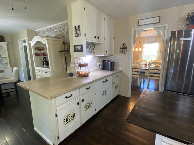 16 Mockingbird Ln, Story, AR 71970 - kitchen with freestanding refrigerator, dark wood-type flooring, white cabinets, light countertops, and backsplash