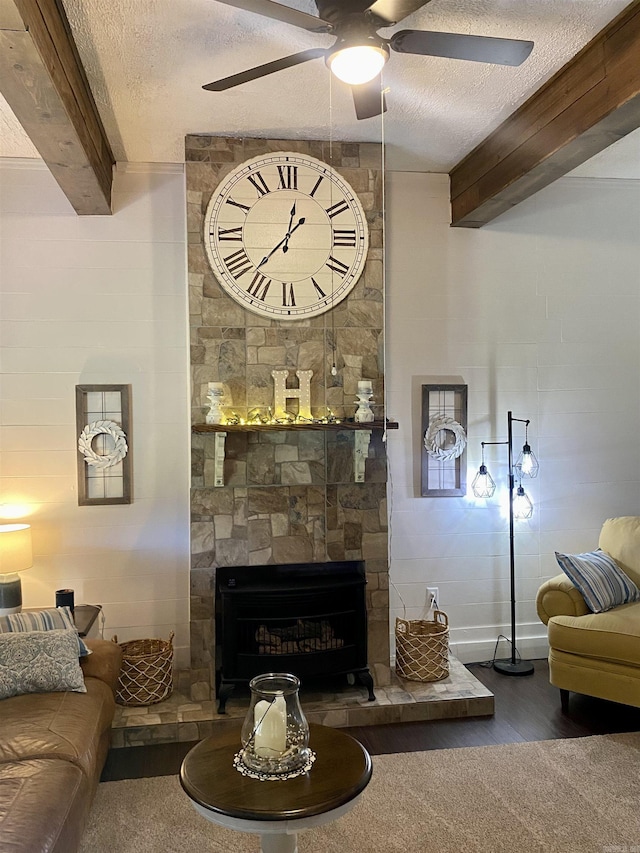 16 Mockingbird Ln, Story, AR 71970 - living area featuring beamed ceiling, ceiling fan, wood finished floors, a textured ceiling, and a stone fireplace