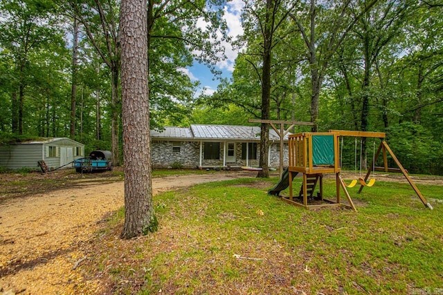 766 Grant 735 Rd, Sheridan, AR 72150 - rear view of house featuring a playground, stone siding, metal roof, and a yard