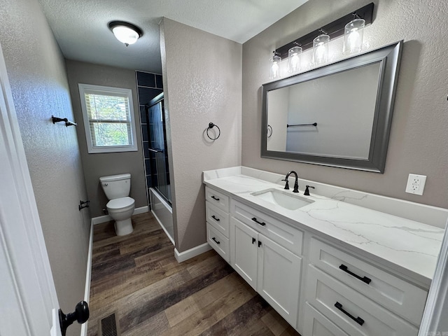 2174 N Main St, Melbourne, AR 72556 - bathroom with a textured wall, vanity, wood finished floors, toilet, and shower / bath combination with glass door