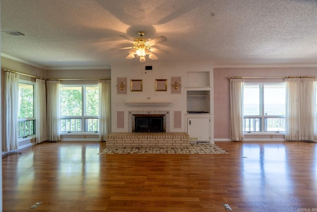 265 Zebulin Dr, Heber Springs, AR 72543 - unfurnished living room with a textured ceiling, ceiling fan, wood finished floors, a brick fireplace, and crown molding