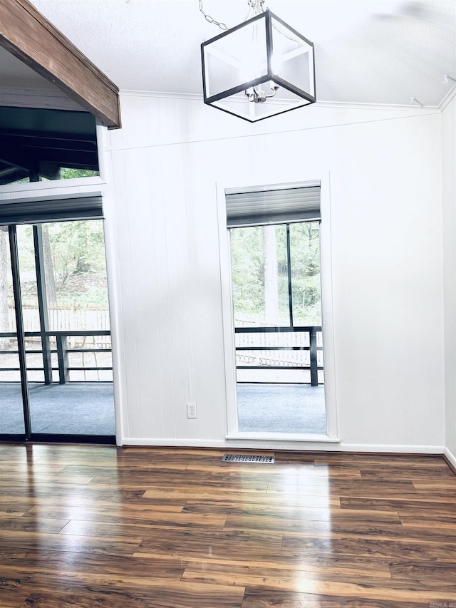 spare room featuring ornamental molding, healthy amount of natural light, wood finished floors, and baseboards