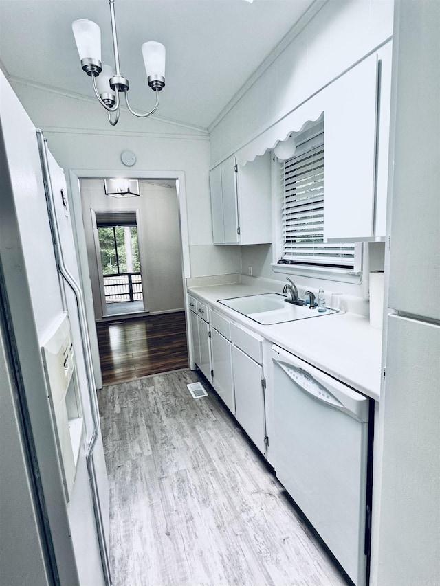 kitchen with white appliances, a sink, light countertops, light wood-style flooring, and ornamental molding