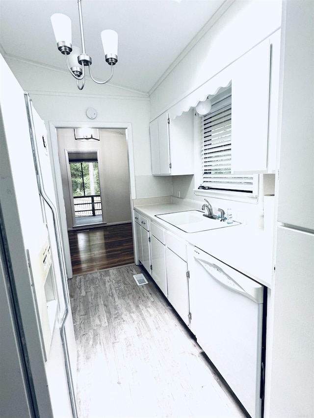 kitchen featuring white appliances, light countertops, crown molding, a sink, and white cabinetry