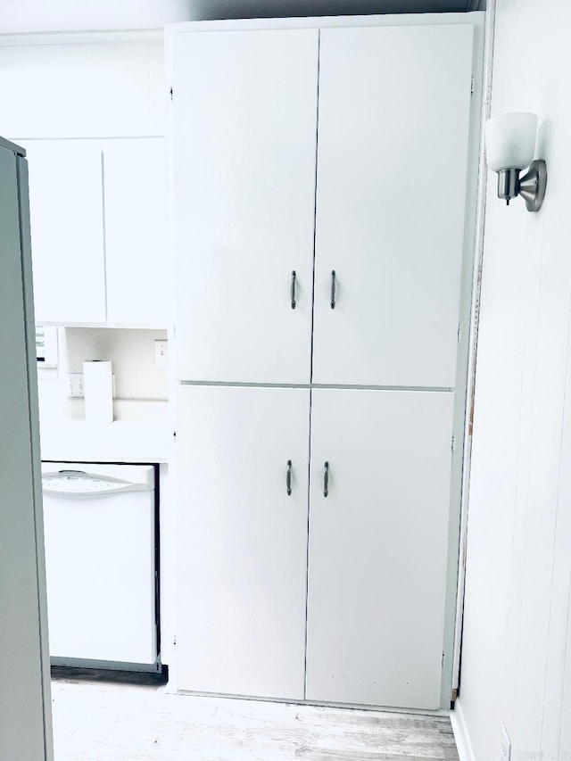 detailed view of dishwasher, wood finished floors, and freestanding refrigerator