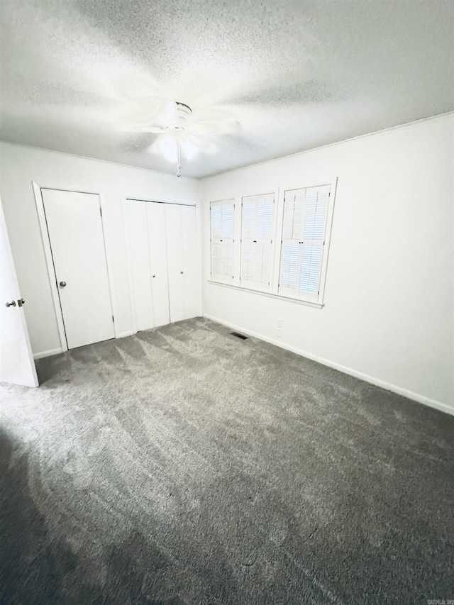 unfurnished bedroom featuring a textured ceiling, carpet floors, baseboards, and ceiling fan