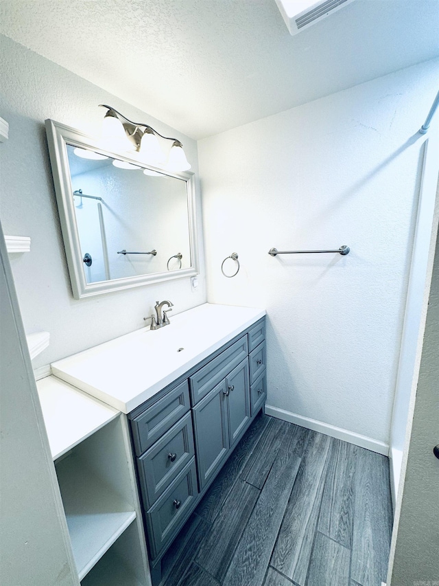 bathroom featuring vanity, wood finished floors, baseboards, and a textured ceiling
