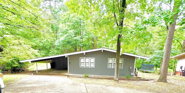 view of front facade featuring a trampoline, driveway, and a carport
