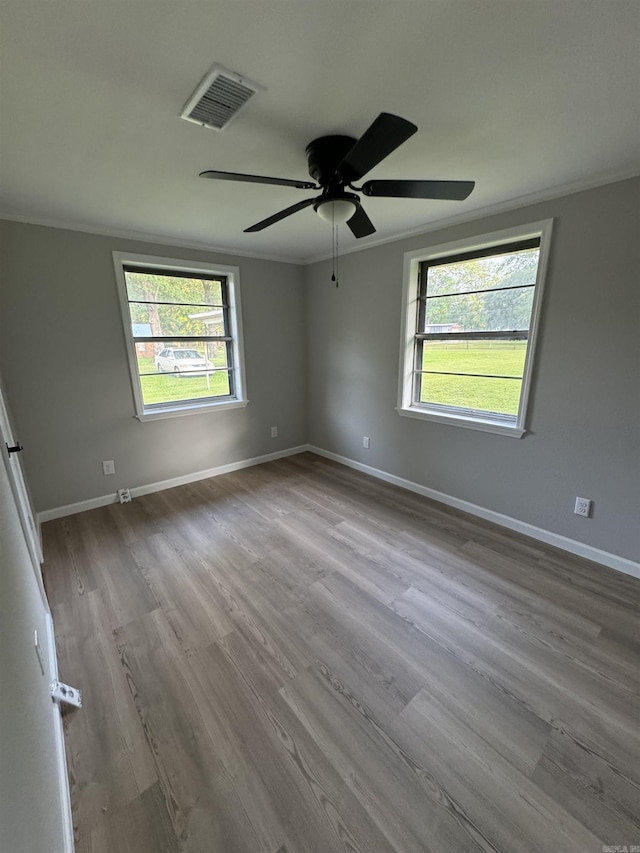 unfurnished room with crown molding, wood finished floors, a ceiling fan, and baseboards