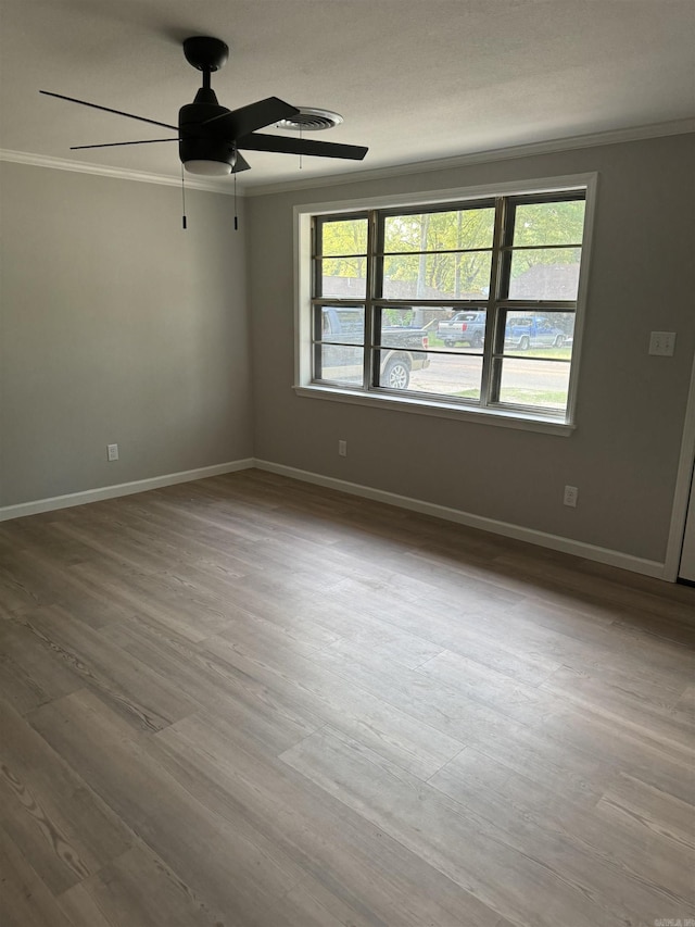 spare room with ornamental molding, a ceiling fan, wood finished floors, and baseboards
