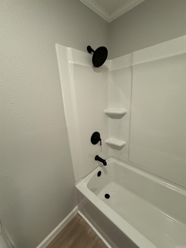 bathroom featuring crown molding, wood finished floors, shower / bathtub combination, and baseboards