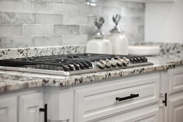 2059 Sloan Lake Dr, Jonesboro, AR 72404 - kitchen view of backsplash, white cabinetry, stainless steel gas cooktop, and light countertops